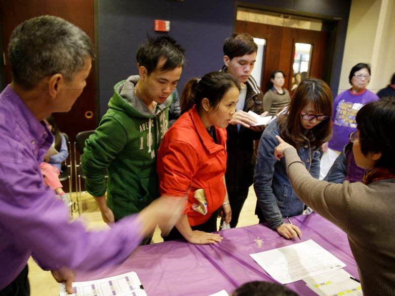 In this photo taken Monday March 31, 2014, applicants are given instructions how to check in for a health care enrollment event at the Oakland Asian Cultural Center in Oakland, Calif.